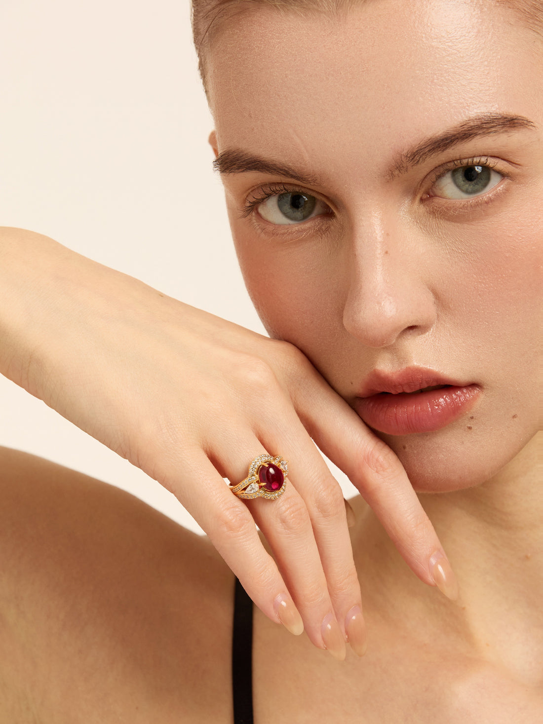 Model wearing a gold-tone ring with a deep red center stone for AURAYA’s sensitive-skin jewelry guide.