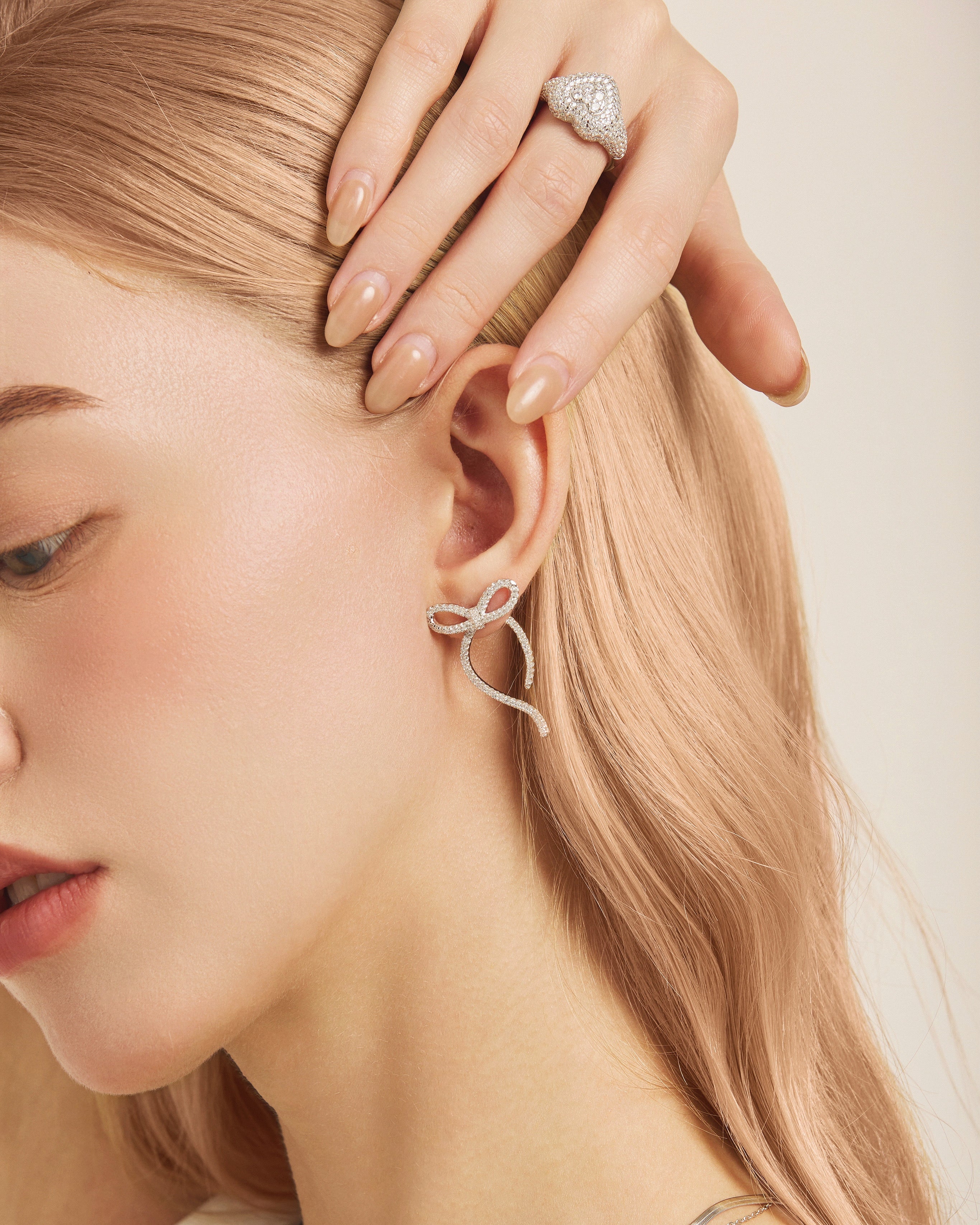 Model wearing a silver statement ring with a long ribbon bow earring
